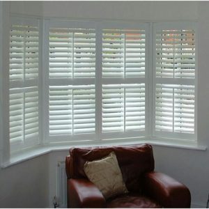 Custom White Shutters Installed in a living room bay window in Whitby, Ontario, enhancing both style and privacy.